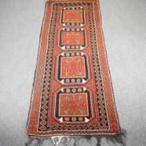 A kazak woollen runner, with a row of four central medallions, on a red ground, 290 x 112cm
