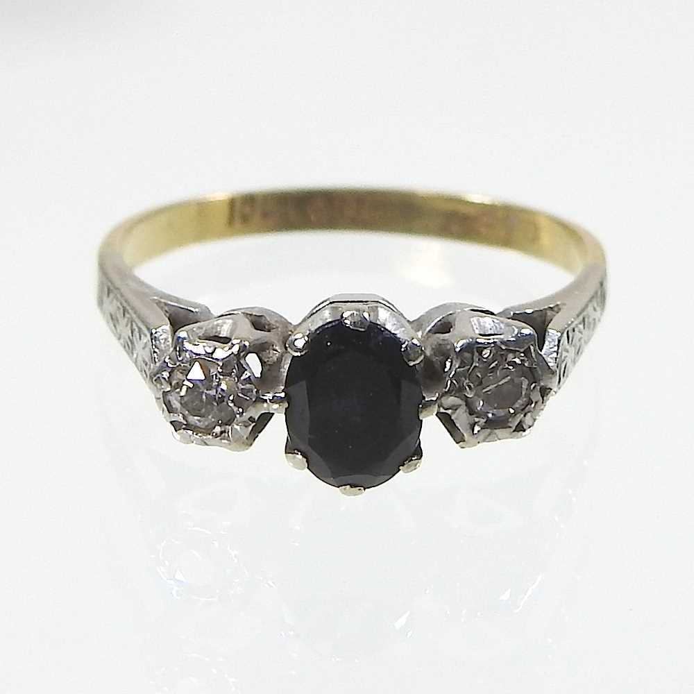 An 18 carat gold and platinum set sapphire and diamond ring, the central oval sapphire flanked by