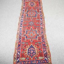 A Caucasian woollen runner, with four central hooked medallions, on a red ground, 299 x 90cm