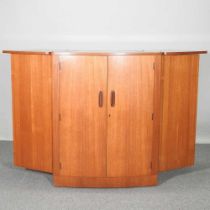 A 1960's teak curved envelope cocktail bar, enclosed by a pair of doors, with a dual hinged top