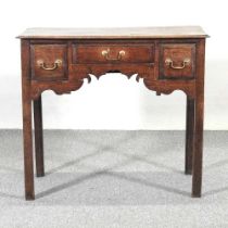 An 18th century oak lowboy, containing three short drawers, above a shaped apron 81w x 48d x 69h cm