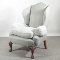 An early 20th century blue upholstered wing armchair, of Queen Anne style, on cabriole legs