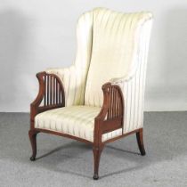 An Edwardian mahogany and cream upholstered high back armchair, on cabriole legs