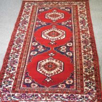 A Persian carpet, with three central medallions, on a red ground, 350 x 175cm