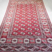A Persian carpet, with rows of medallions on a red ground, 390 x 250cm