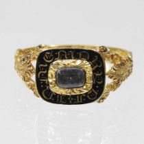 A Victorian enamelled mourning ring, inset with plaited hair, within a scrolled surround,