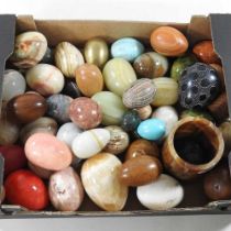 A collection of polished hardstone eggs, together with a stone chess board and various pots