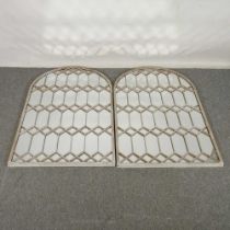 A pair of grey painted metal framed wall mirrors, each of arched shape, with lattice decoration,
