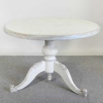 A rustic cream painted pine circular dining table, on a splayed base 110w x 76h cm