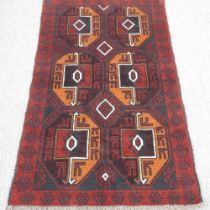 A baluchi rug, with two rows of medallions, on a red ground, 137 x 86cm