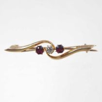 A 15 carat gold three stone diamond and ruby bar brooch, of crossover design, 3.6g, 4cm wide