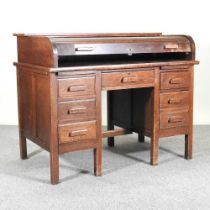 A 1920's oak pedestal desk, with a tambour top, over seven short drawers 123w x 76d x 100h cm