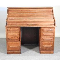 A 1920's oak tambour top pedestal desk, with a fitted interior, containing short drawers 122w x