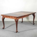 An early 20th century walnut wind-out extending dining table, with an additional leaf, on cabriole