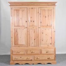 A modern pine triple wardrobe, with an arrangement of five drawers below 162w x 57d x 211h cm