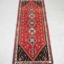 A Persian runner, with a row of five central medallions, on a red field, 250 x 92cm