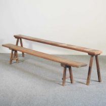 An early 20th century rustic pine bench, on splayed legs, 214cm wide, together with another