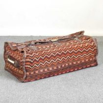 A large Caucasian carpet bag, with leather straps, together with a Christian Lacroix cushion,