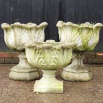 A pair of cast stone pedestal garden urns, 56 cm high, together with another smaller (3)