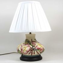 A Moorcroft pottery table lamp, decorated in the Pink Magnolia pattern, with a cream shade, 41cm