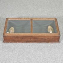 An early 20th century oak museum display cabinet, with a hinged glazed top, together with a pair