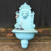 A blue painted cast iron wall mounted water fountain, with lion mask decoration, 75 cm high