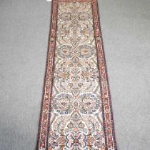 A Persian runner, with all over floral designs, on a cream ground, 404 x 77cm