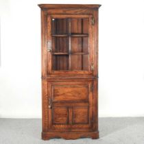 A modern oak standing corner cabinet, with a glazed upper section 83w x 63d x 186h cm