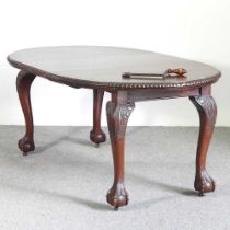 An early 20th century wind out extending dining table, of oval shape, on a claw and ball feet,