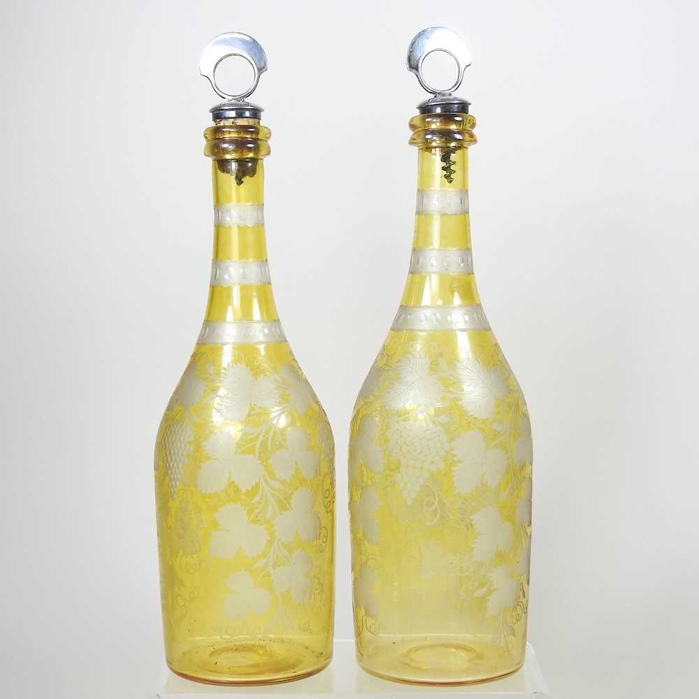 A pair of 19th century yellow overlaid glass wine bottles, each etched with hops, having a silver