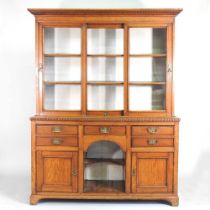 A late Victorian light oak dog kennel dresser, with a glazed plate rack, containing an arrangement