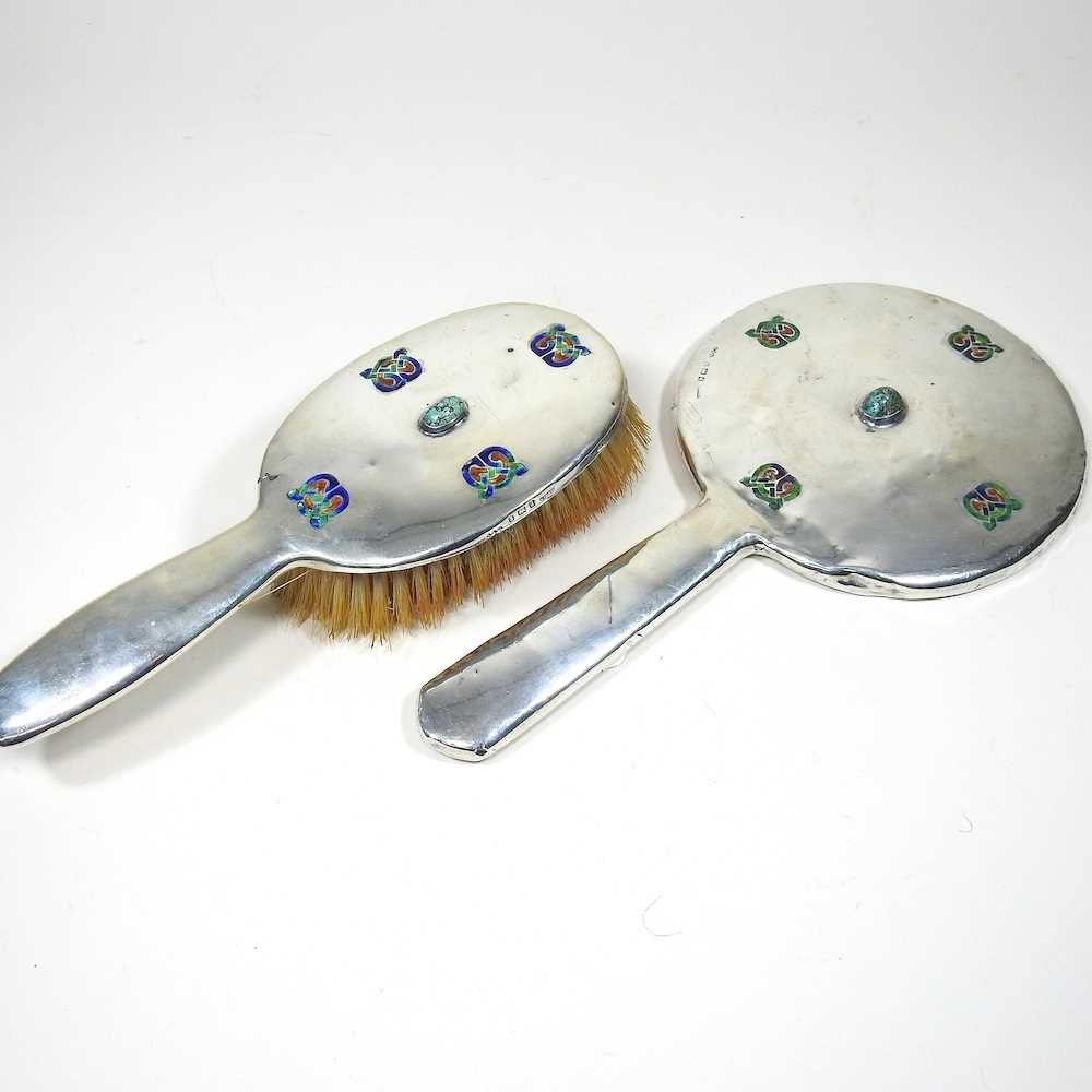 An Edwardian silver hand mirror, 28cm long and brush, 24cm long, each inset with a Ruskin style