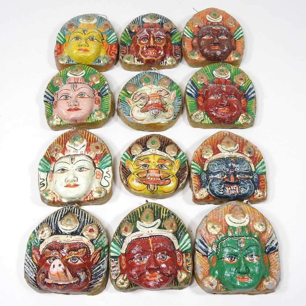 A set of twelve Nepalese painted plaster faces of deities, 7cm high (12)