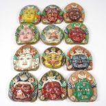 A set of twelve Nepalese painted plaster faces of deities, 7cm high (12)
