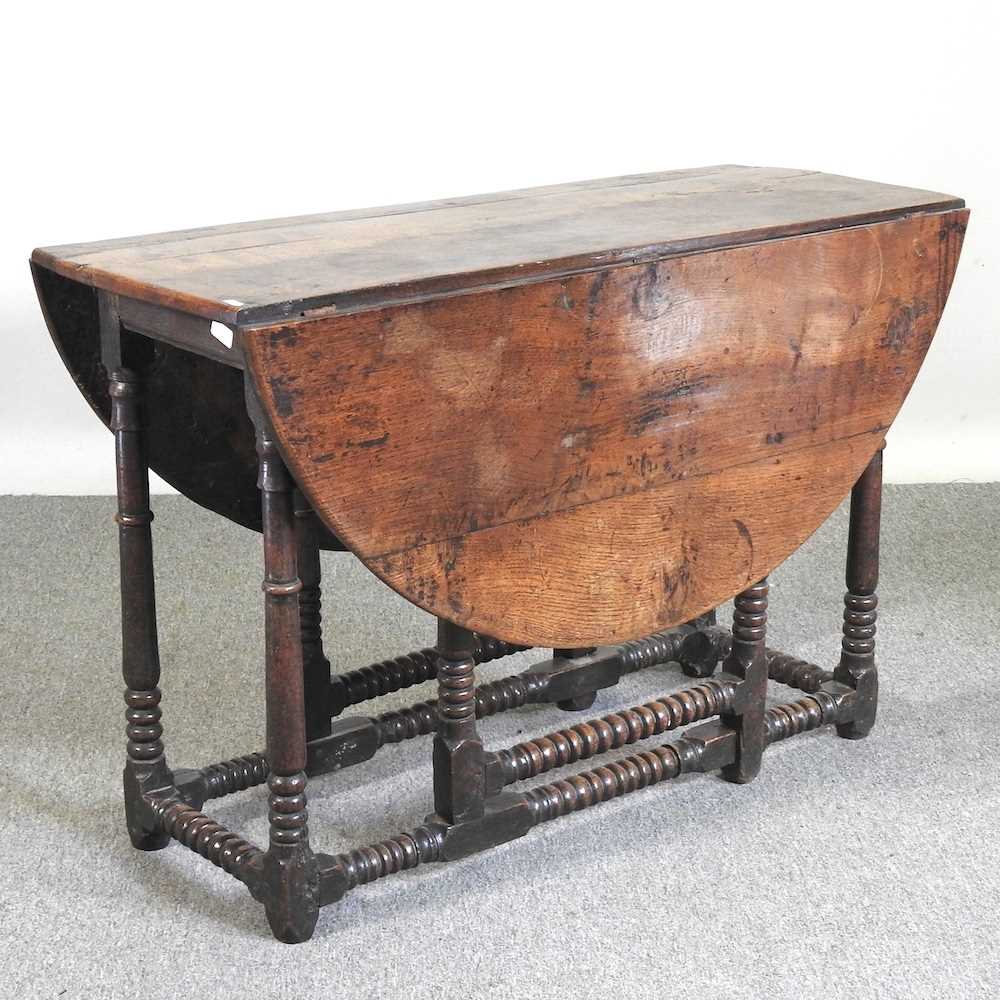 An 18th century oak gateleg table, with a hinged oval top, on bobbin turned legs 108w x 44d x 72h cm