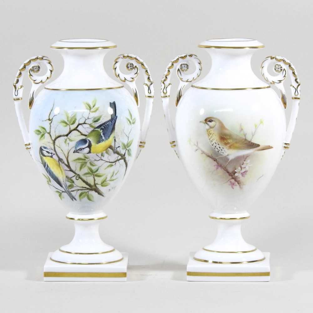 A pair of Royal Worcester porcelain vases, each of twin handled baluster shape, painted with a