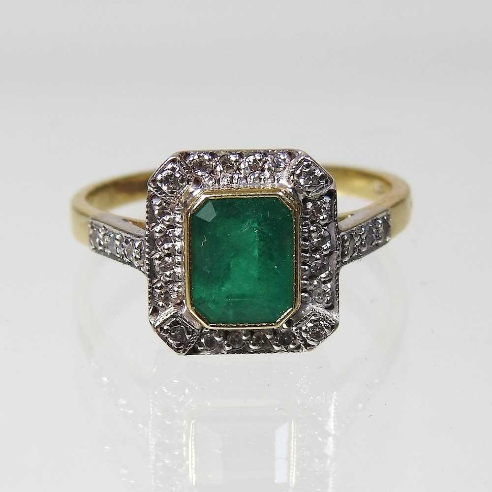 An unmarked emerald and diamond cluster ring, of Art Deco design, with a central baguette cut