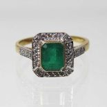 An unmarked emerald and diamond cluster ring, of Art Deco design, with a central baguette cut