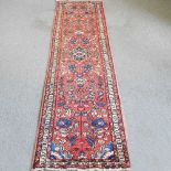 A Persian Sarouk runner, with foliate designs, on a red ground, 330 x 80cm