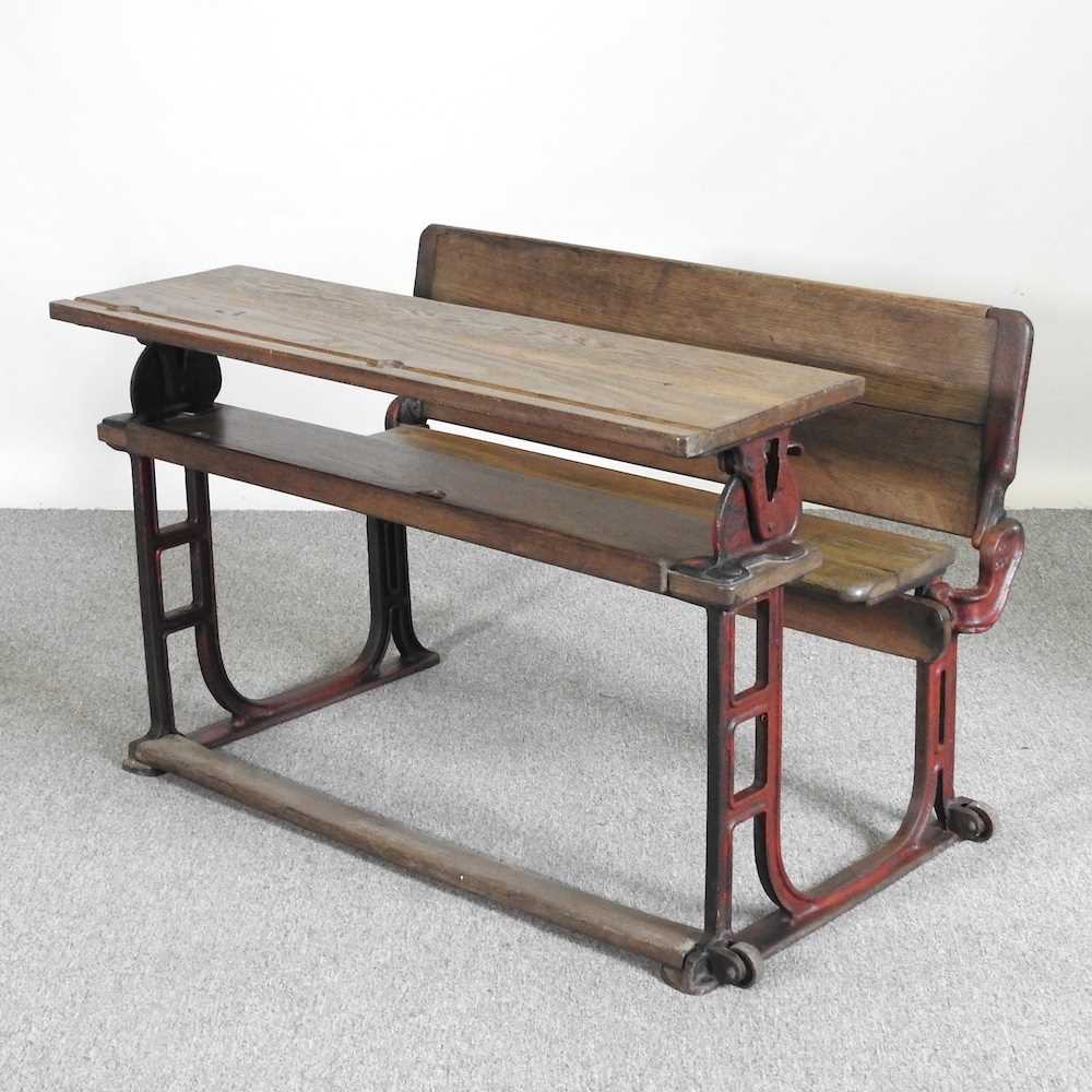 An early 20th century wooden school desk, on an iron base, stamped LEC 102w x 70d x 66h cm