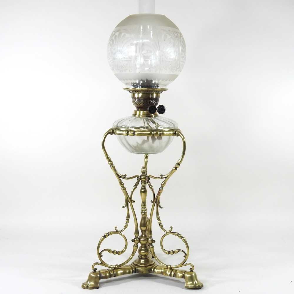 An ornate 19th century brass oil lamp, with an etched glass shade, clear glass font and scrolled