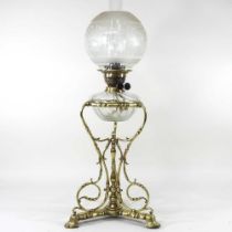 An ornate 19th century brass oil lamp, with an etched glass shade, clear glass font and scrolled