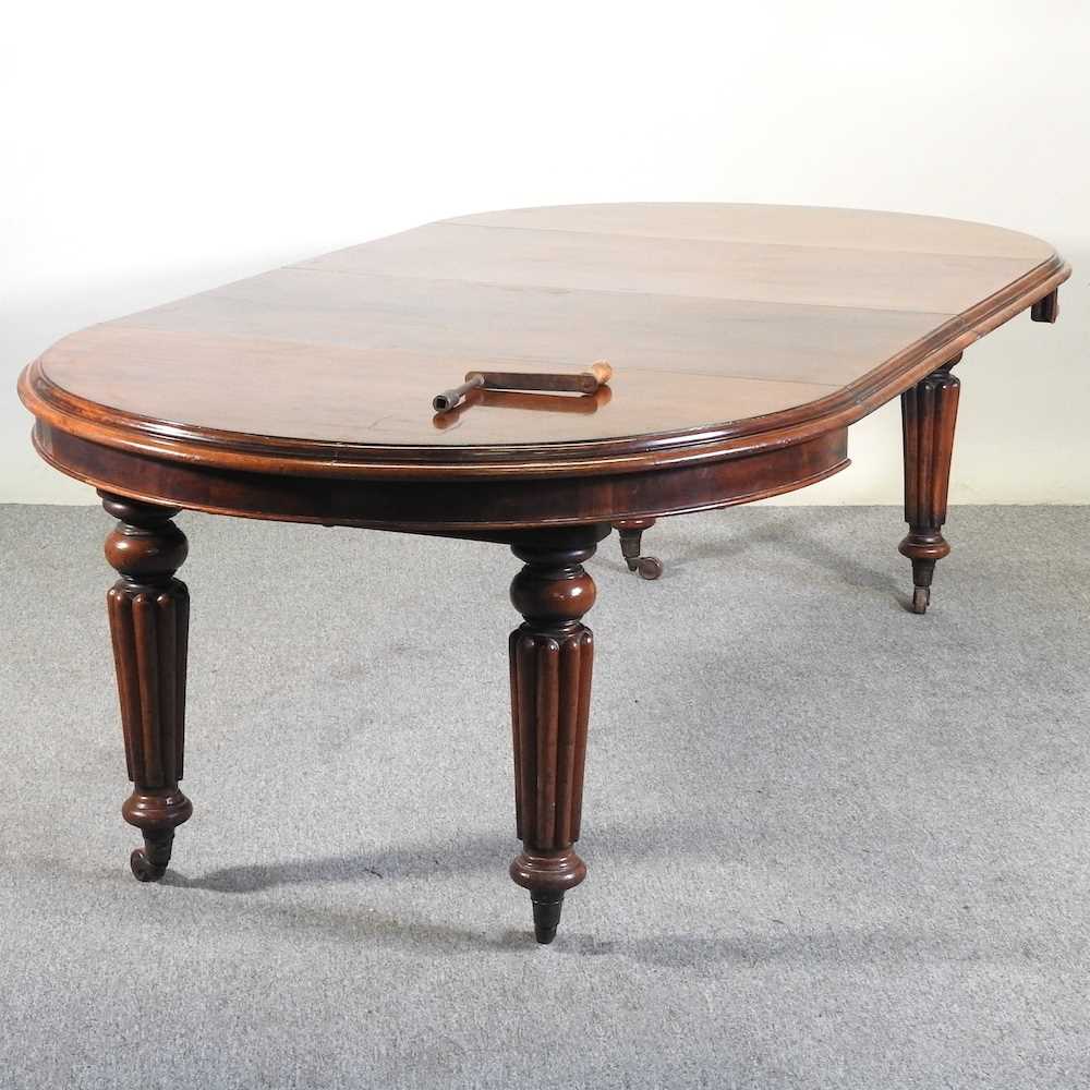A Victorian mahogany oval wind out extending dining table, on turned and reeded legs, with two