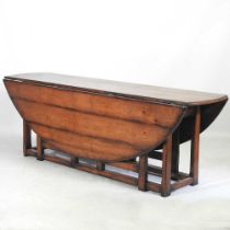 A large 18th century style oak wakes table, 20th century, the hinged oval top with a double gateleg,