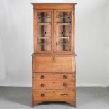 An early 20th century oak bureau bookcase, with stained leaded glass 92w x 41d x 206h cm