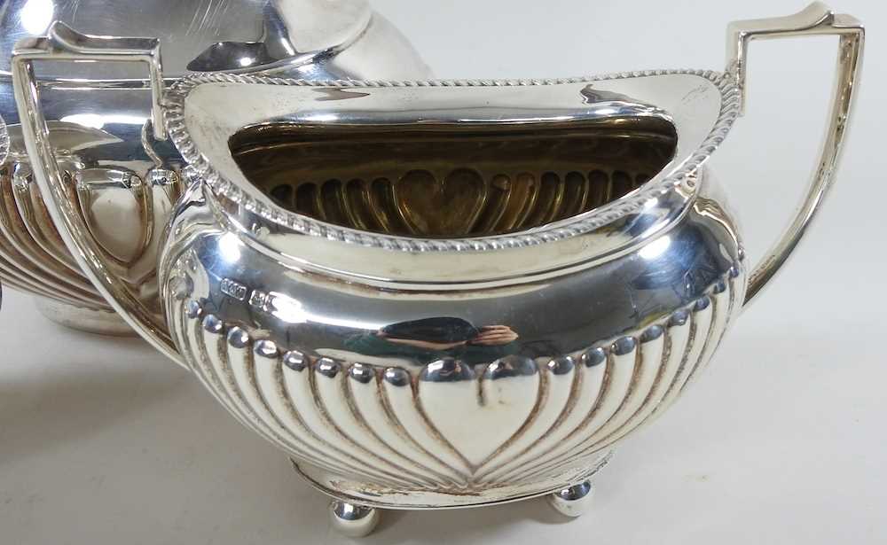 An Edwardian silver three piece tea service, with half gadrooned decoration, comprising a teapot, - Image 5 of 9
