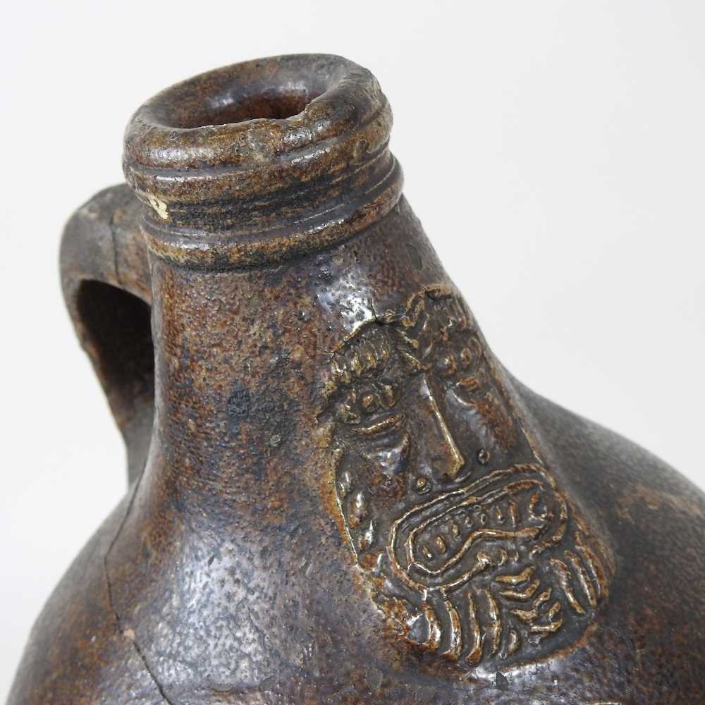 A 17th century German salt glazed stoneware bellarmine or Bartmann krug, of plain shape with a - Image 3 of 10