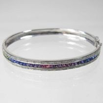 A 9 carat white gold and fancy sapphire bangle, of hinged design, set with a single row of multi