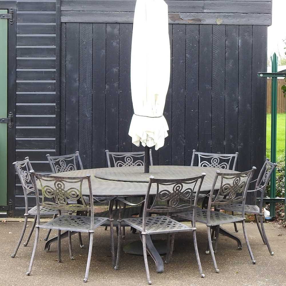 A large cast metal oval garden table, together with a set of eight garden chairs and a parasol base,