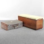 An early 20th century suitcase, together with a Victorian ottoman, with a padded top (2)